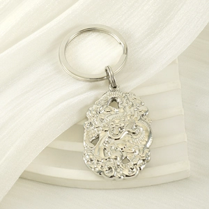 Porte-clés pendentif dragon argenté au fini métallique sur fond de soie blanche