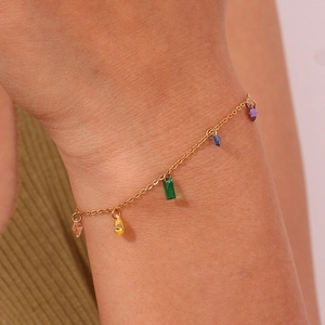 Detail of a 18K gold-plated bracelet with five colorful zircon stones on a model's wrist