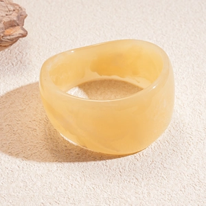 Close-up of a wide translucent ginger resin bangle with natural cloudy marble texture