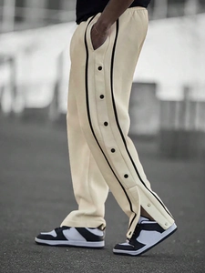 Detail of beige men's jogger with black side stripes and side button row design