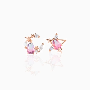 Dettaglio macro di orecchini asimmetrici a stella e luna con cristalli sfumati rosa-azzurro