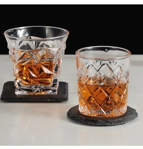 Macro shot of whiskey glasses on natural black slate coasters with textured stone surface