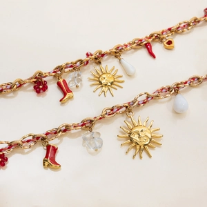 Detail view of gold chain necklaces with red boots, sun charms and woven ropes