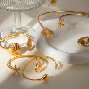 Ocean themed 18k gold plated stainless steel open bangle with seashell and starfish charms