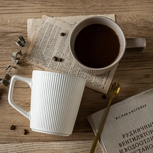 Japanese style relief ceramic mugs in white and beige on a rustic wooden desk