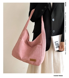 Close-up of pink corduroy shoulder bag showing vertical texture and logo patch