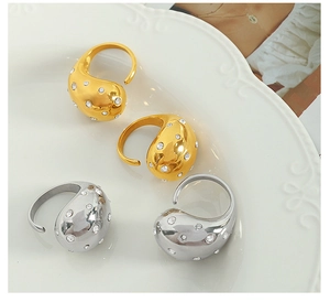 Detail of gold and silver teardrop rings with micro-inlaid diamonds on a white tray