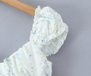 Detail of floral puff sleeves and ruffled elastic texture on white and blue vintage top