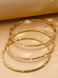 Détail de trois joncs plaqués or 24K avec facettes torsadées et reflets étoilés