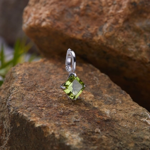 Macro shot of S925 sterling silver pendant with square green gemstone on rock