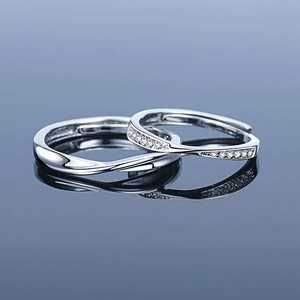 Polished Mobius silver couple rings set with micro-pave diamonds on blue reflection surface