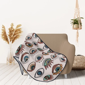 Detail of bohemian evil eye pattern flannel blanket draped over a cozy cream sofa chair