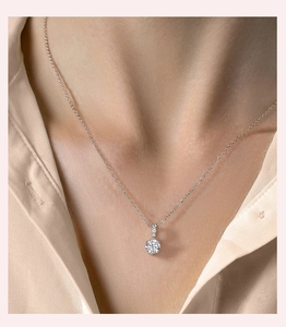 Elegant silver pendant necklace with moissanite stone worn by a female model on a light shirt
