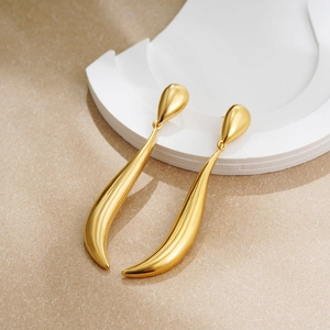 Detail of 18k gold plated long teardrop earrings with elegant curved lines and metal luster