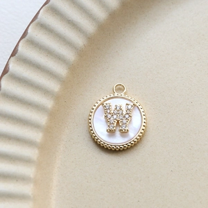 Detailed macro view of a gold-plated letter W shell pendant with inlaid cubic zirconia
