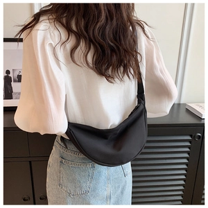 Minimalist black nylon crescent moon bag shown worn by a model in casual daily styling