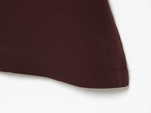 Close-up of wine red backless dress showing fine fabric texture and neat hemline stitching