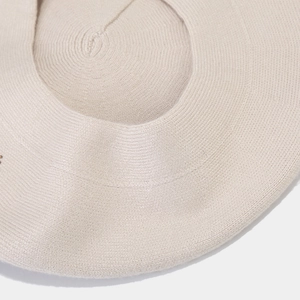 Close-up of spiral knitted pattern on the beige winter beret showing thick texture
