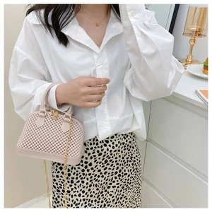 Close-up of pink PVC shell bag with grainy texture and golden chain strap for women