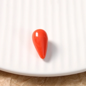 Detail of teardrop resin bead in orange-red with polished smooth coral texture