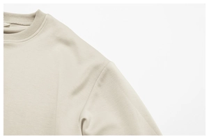 Gros plan sur l'encolure côtelée et la texture douce du sweat-shirt col rond crème