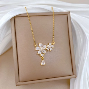 Detailed view of gold flower necklace with zircon crystals in a brown jewelry box