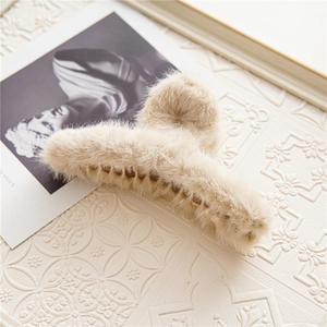 Detail van een beige pluche haarklem op een witte achtergrond met textuur en kaart