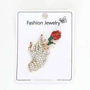 Detailed close-up of rose brooch with red crystals and green enamel on a golden stem