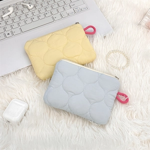 Close-up of quilted macaron colored fabric pouches with ring zippers on plush surface