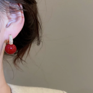 Close-up of elegant red sphere earrings with gold hoop and micro-pave white zircon stones