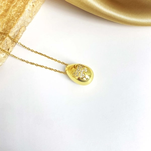Détail d'un pendentif goutte en plaqué or avec incrustation papillon en micro-zircon