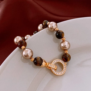 Close-up of beaded necklace with tiger eye stones, pearls, and a sparkling zircon clasp