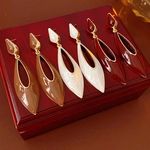 Detail of three pairs of vintage enamel drop earrings in brown, white and burgundy colors