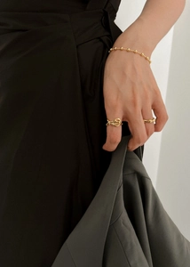 Close-up of golden 925 silver bow rings and beaded bracelet on hand in elegant style