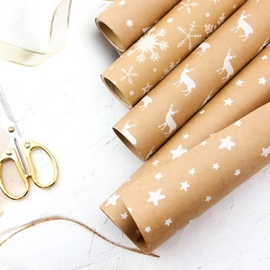 Brown kraft Christmas wrapping paper rolls with white snowflake and reindeer patterns