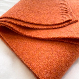 Close-up of bright orange knitted scarf texture showing soft and fuzzy wool-like fabric