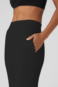 Dettaglio dei pantaloni yoga neri a vita alta con una pratica tasca laterale a coste