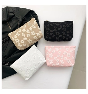 Detailed close-up of textured floral fabric cosmetic bags in beige, black, and white