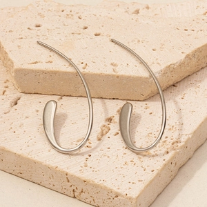 Close-up of silver 304 stainless steel curved drop earrings on natural stone background