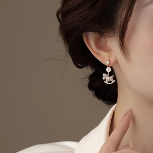 Detail shot of gold plated rocking horse earrings with pearls and crystals on a model
