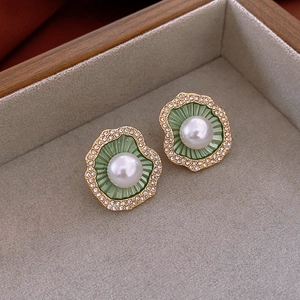 Detailed macro of vintage flower earring with green enamel, pearl, and tiny rhinestones