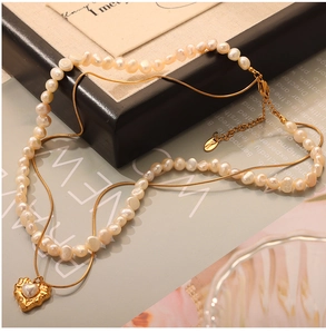 Macro view of gold plated heart pendant with freshwater pearl on a delicate chain