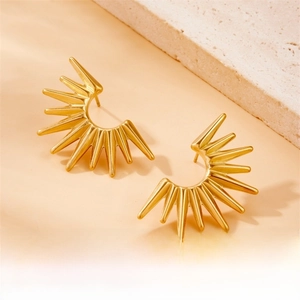 Macro shot of gold semi-circle sunburst earrings with matte texture on marble surface