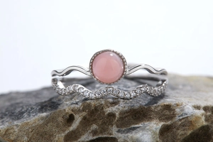 Detail of s925 silver double-layered wave ring with pink gemstone and small diamonds