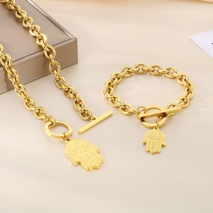 Makroaufnahme von Goldschmuck-Set mit Hamsa-Hand-Anhänger und OT-Knebelverschluss-Detail