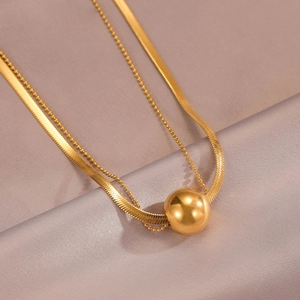Macro shot of minimalist gold double layer ball pendant necklace on champagne silk