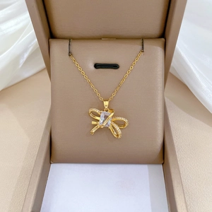 Macro shot of gold bow necklace with rectangular zircon inlay in a brown jewelry box