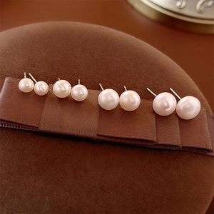 Detailed view of four different sized freshwater pearl earrings on brown velvet display