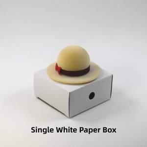 Close-up of a mini straw hat jewelry box with a red ribbon on a white paper box