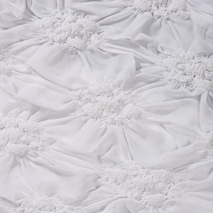 Detail of white cropped top featuring textured pinch pleat fabric and floral ruffles